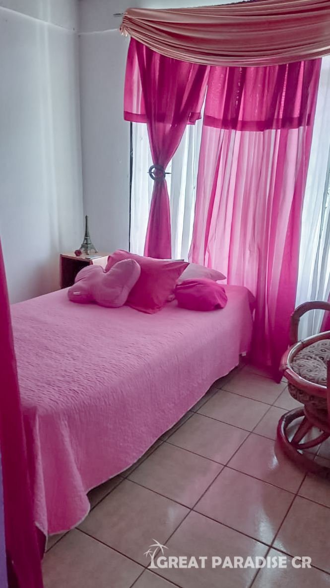 Dormitorio con ropa de cama y cortinas rosadas en Casa Barrio San Francisco